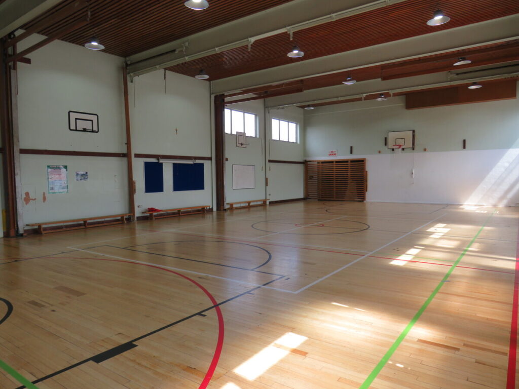 School sports hall with basketball courts and benches by the sports hall walls.
