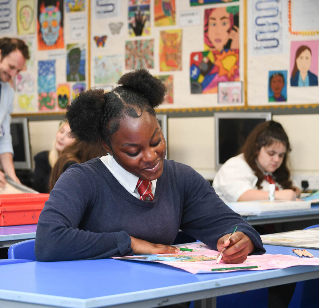 Class of pupils sitting down at desk's in classroom with open books. Pupil writing looking forward down at book.