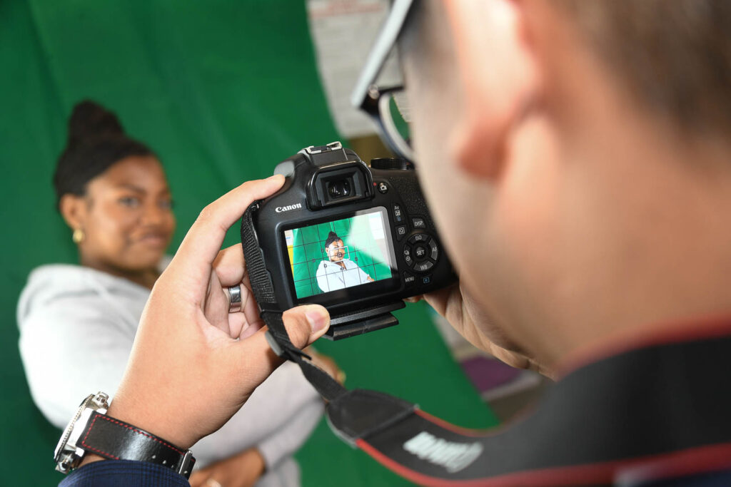 Pupil/student taking picture, of pupil in media space with green screen drop back.