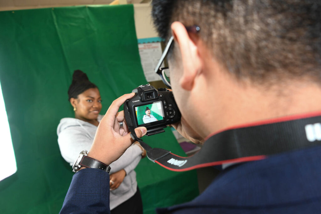 Pupil/student taking picture, of pupil in media space with green screen drop back.