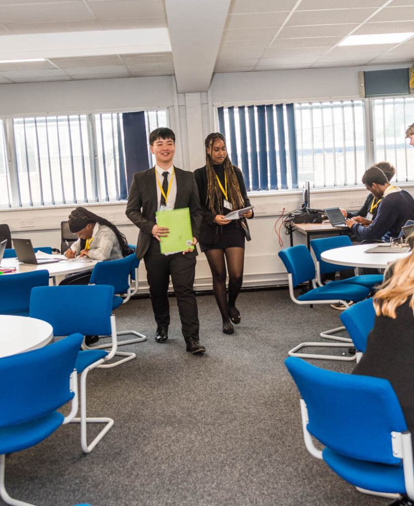 Six form students walking through work space in classroom.