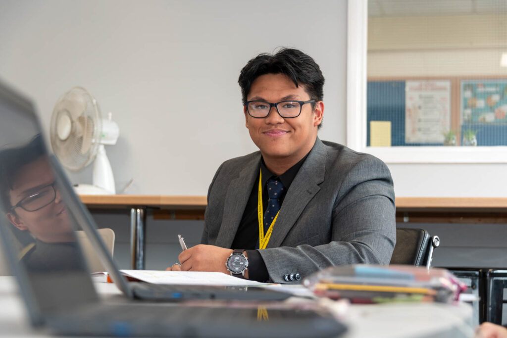 Six form pupil/student working at desk/table, writing down work.